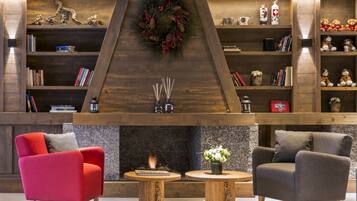 A modern interior with a fireplace, bookshelves, and two armchairs.