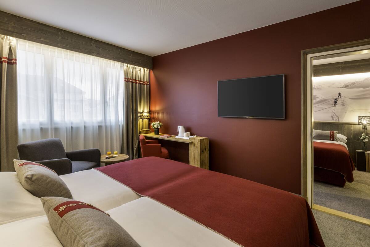 A hotel room with a large bed, a desk, a chair, and a television.