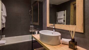 A modern bathroom with a large white sink, a glass shower enclosure, and a wooden vanity.