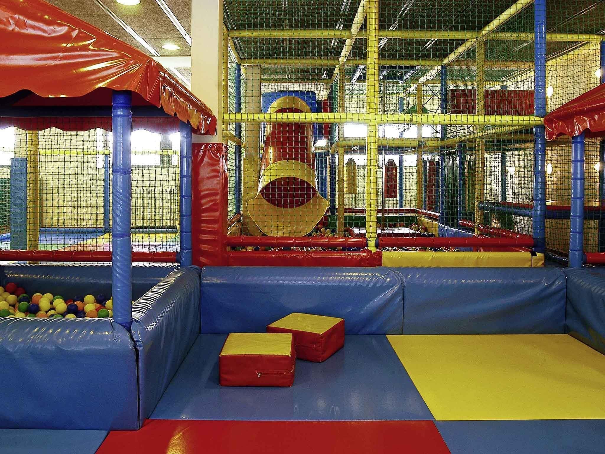 An indoor play area with padded walls, a ball pit, and a climbing structure.