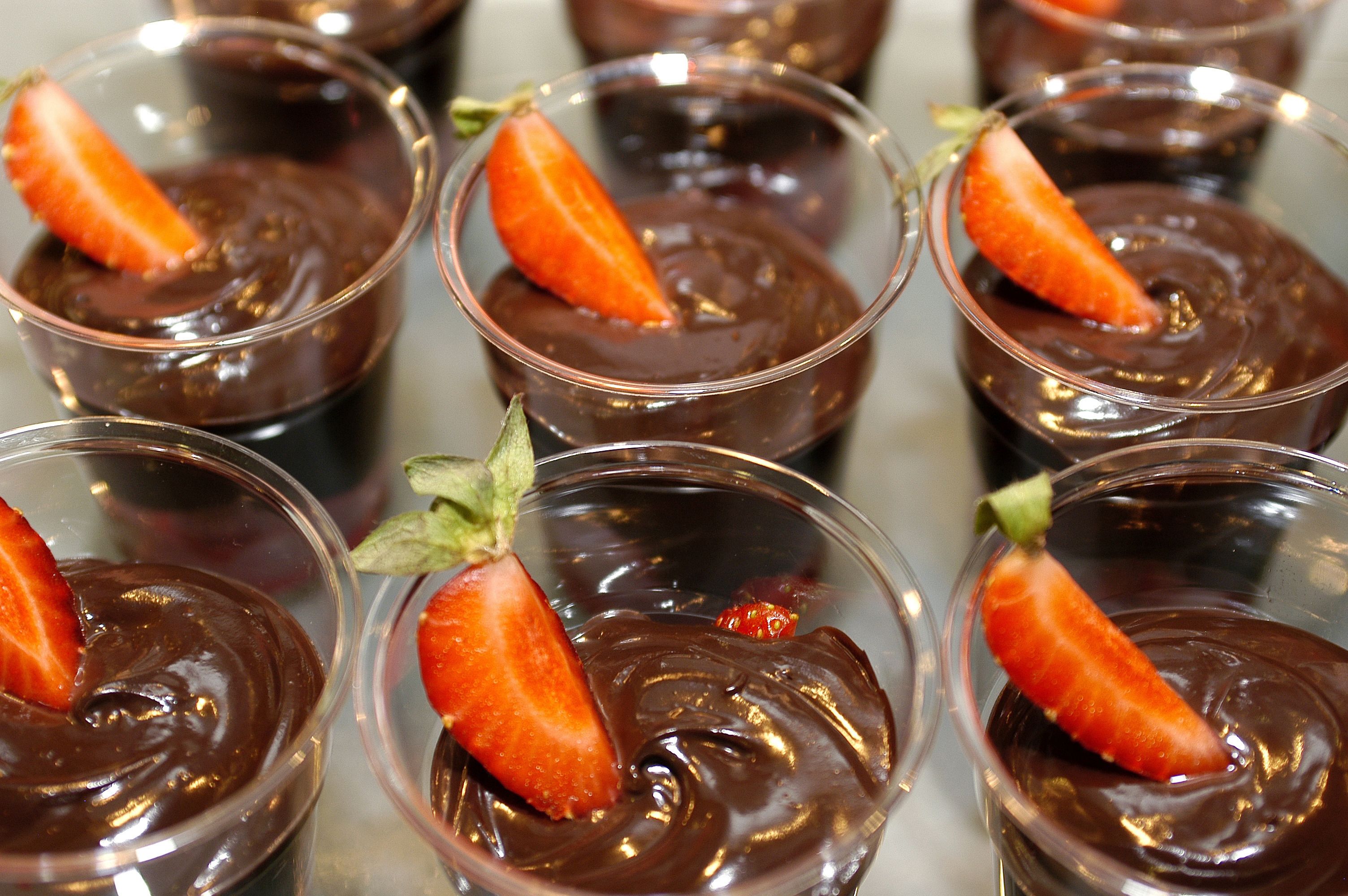 Varios vasos de postre de chocolate adornados con fresas.
