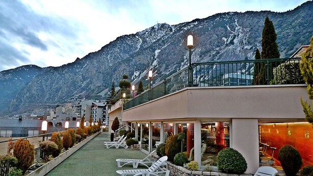 A hotel with a rooftop terrace, lounge chairs, and a mountain backdrop. - Novotel Andorra (Andorra la Vella)