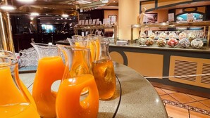 A buffet area with orange juice dispensers and a variety of food items. - Novotel Andorra (Andorra la Vella)