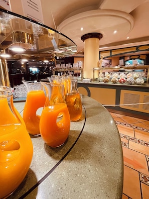 A buffet area with orange juice dispensers and a variety of food items. - Novotel Andorra (Andorra la Vella)