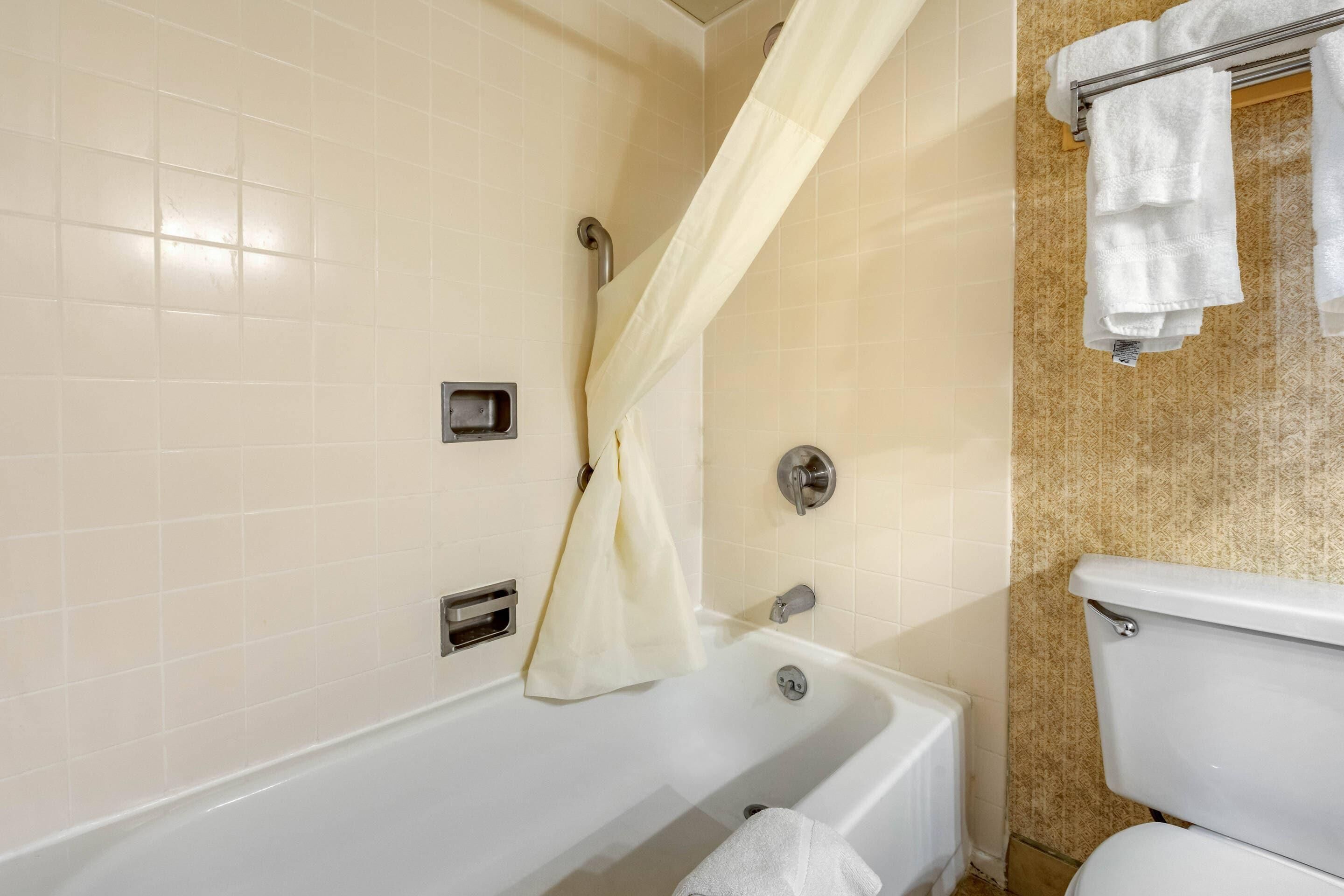 A bathroom with a bathtub, a toilet, and a shower curtain.