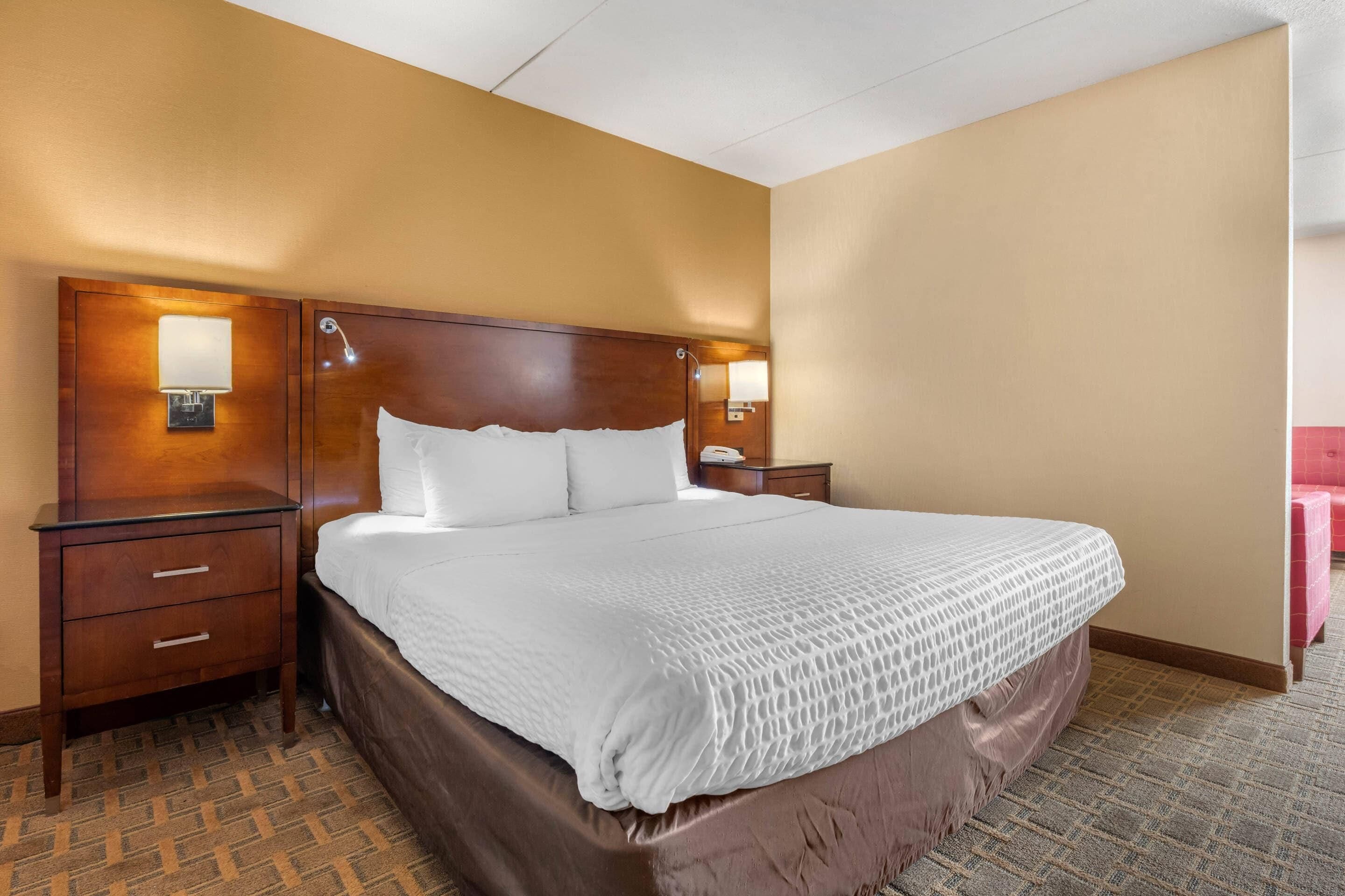A hotel room with a large bed, two bedside tables, and a nightstand.
