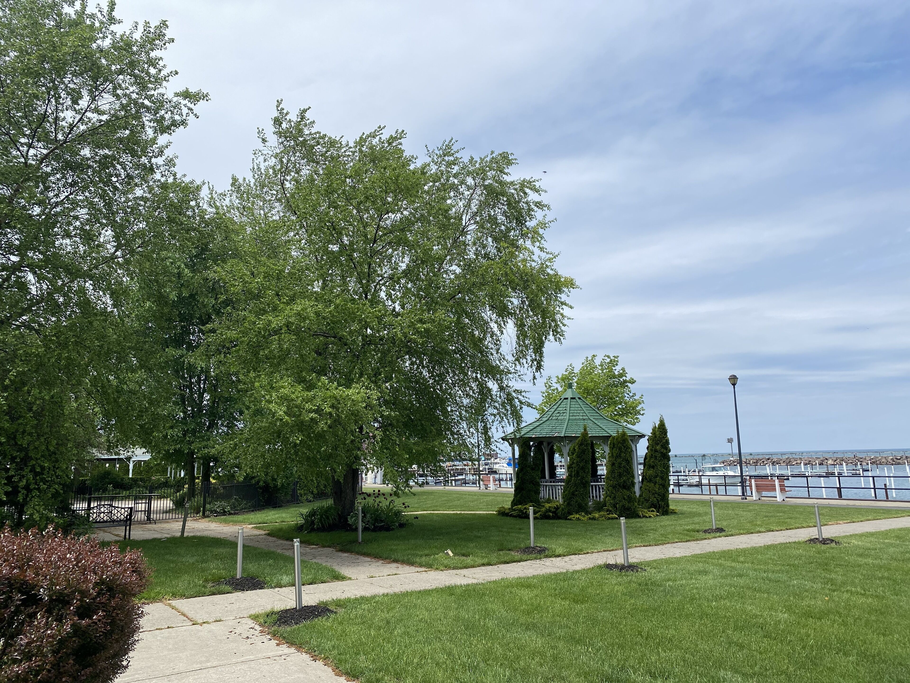 Un parc avec un kiosque, un sentier et une étendue d’eau en arrière-plan.