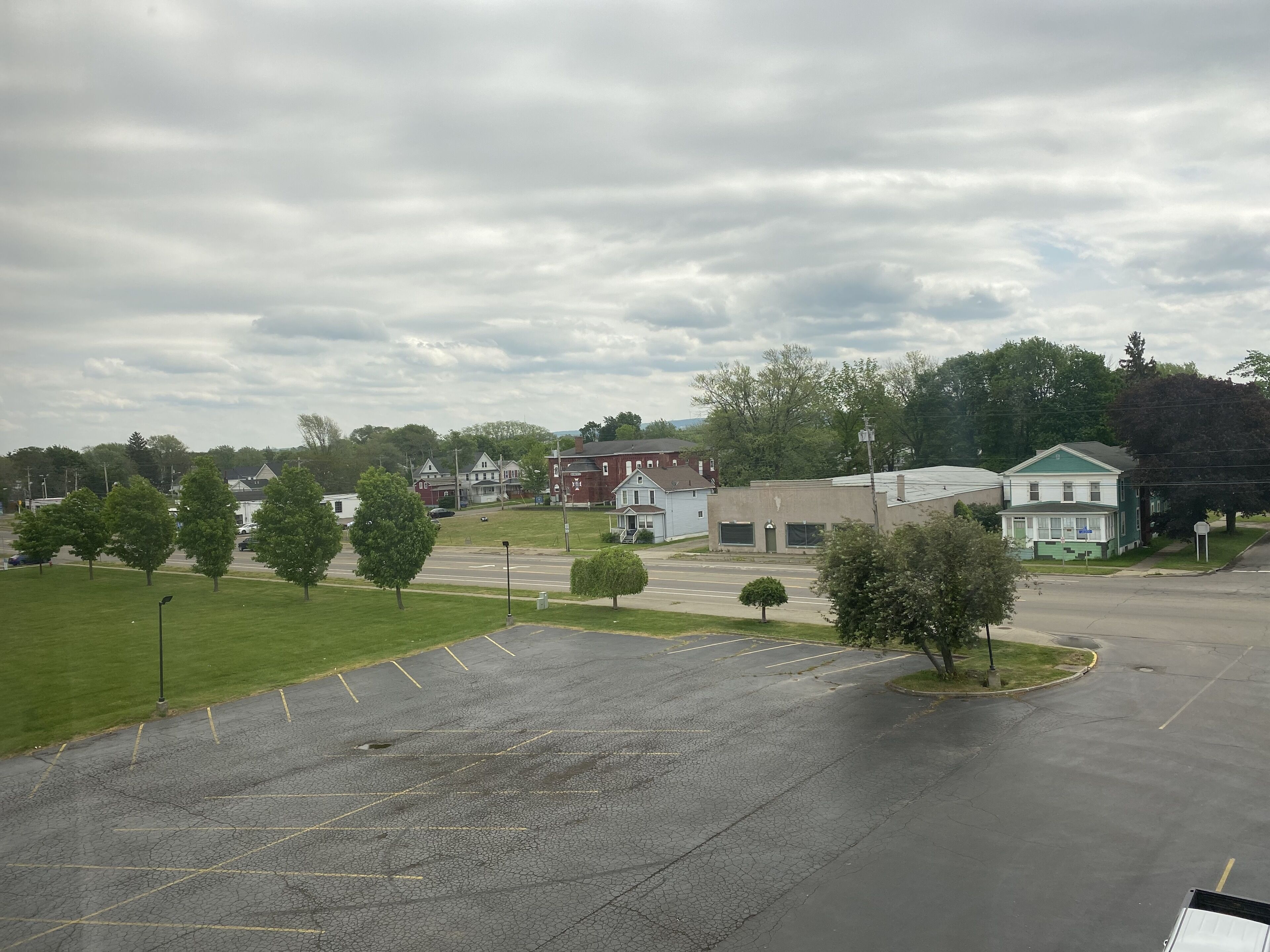 A parking lot with multiple parking spaces and a grassy area with trees.