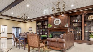 A spacious lobby with a fireplace, leather sofas, a dining area, and a bookshelf filled with books and decorative items.