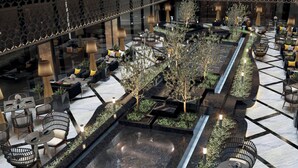 Un espace extérieur aménagé avec des tables et des chaises, une fontaine ou un autre élément aquatique, et des plantes décoratives.
