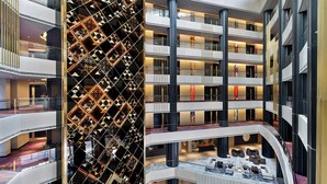 Un atrium d’hôtel à plusieurs niveaux, doté d’une colonne centrale, de nombreux balcons et d’un mur orné de motifs.