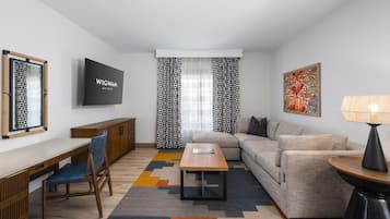 A modern living room with a flat-screen TV, a sofa, a coffee table, and a lamp.