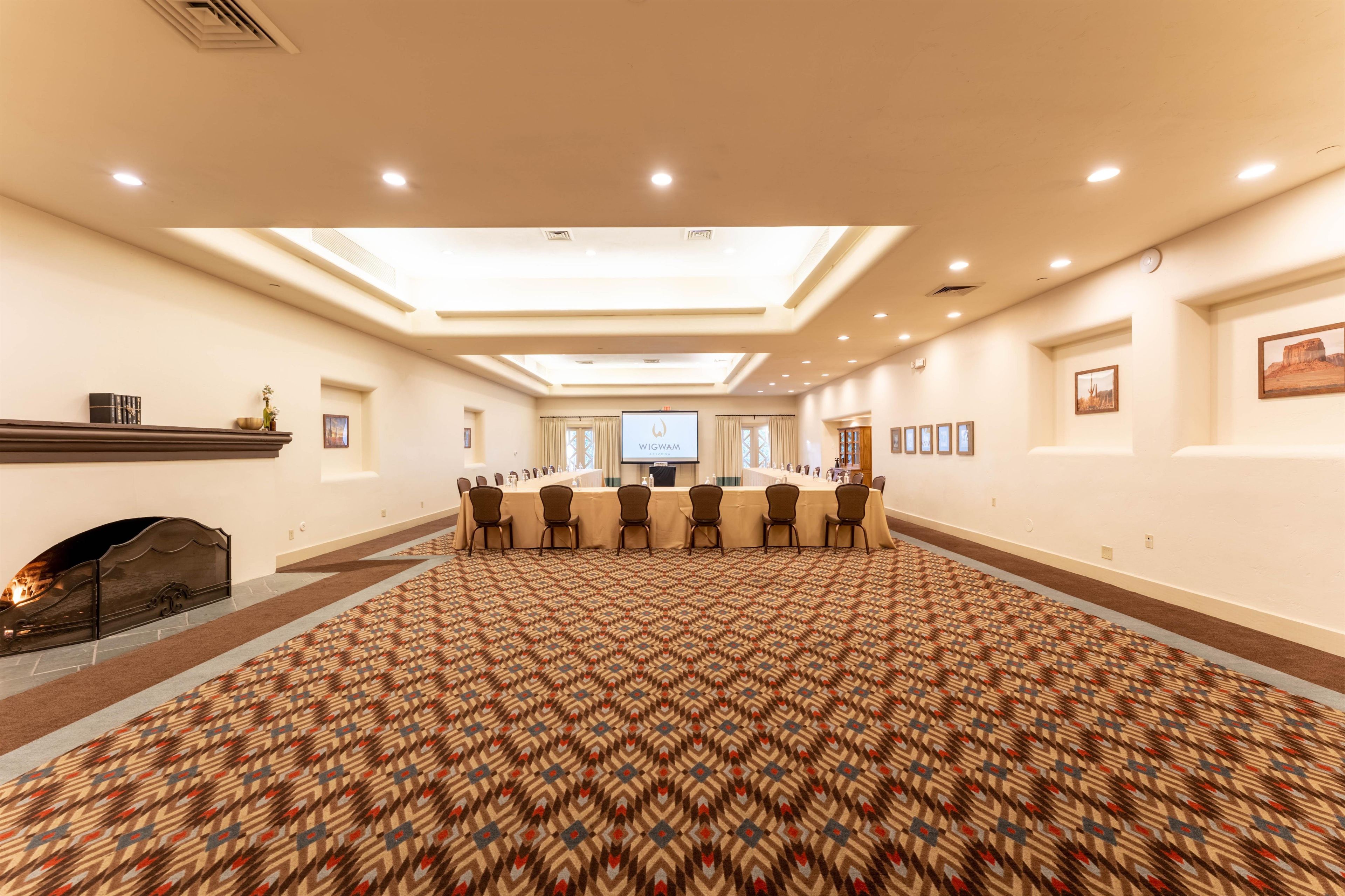 A conference room with a long table, chairs, a fireplace, and a large screen.