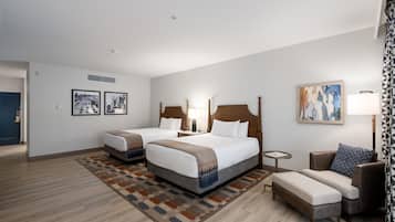 A hotel room with two beds, a sofa, a small table, and artwork on the walls.