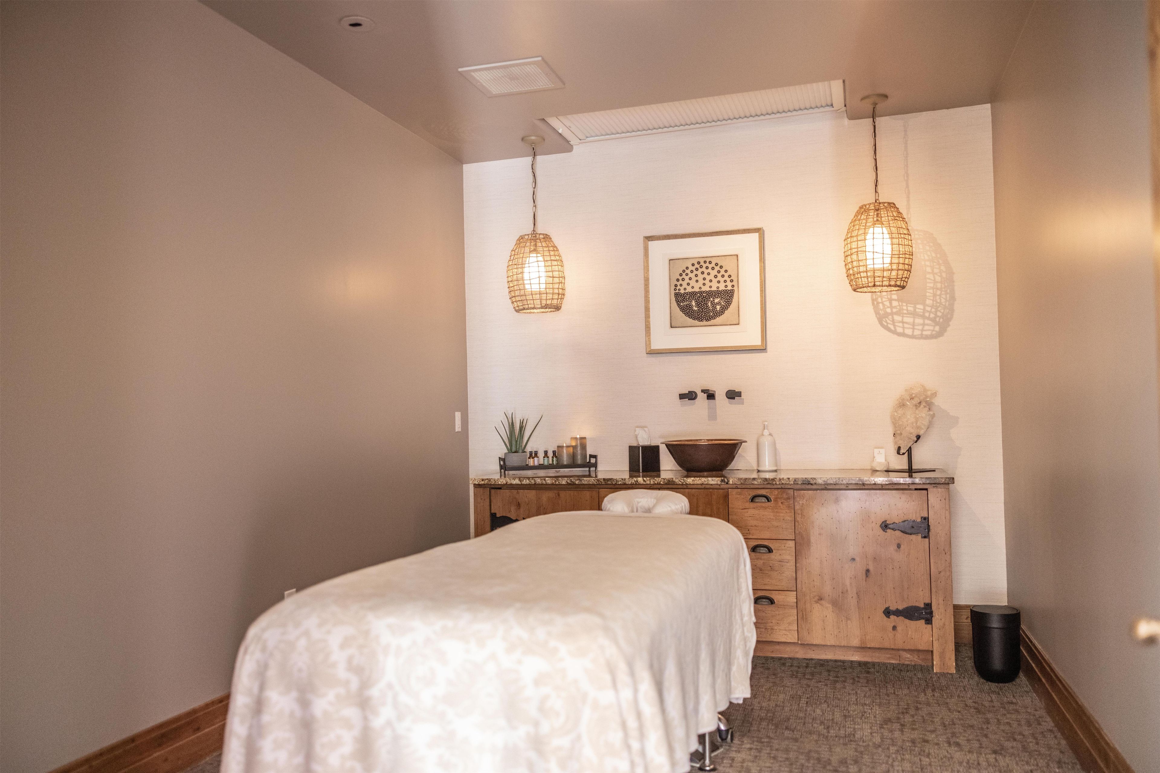 Une chambre à coucher avec un lit, une commode en bois et deux lampes suspendues.