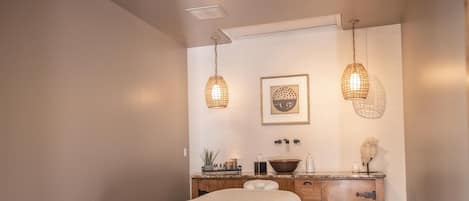 Een slaapkamer met een bed, een houten dressoir en twee hanglampen.