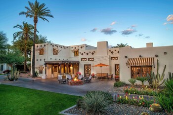 A well-maintained outdoor area with palm trees, a pathway, and a building with a beige facade. at The Wigwam