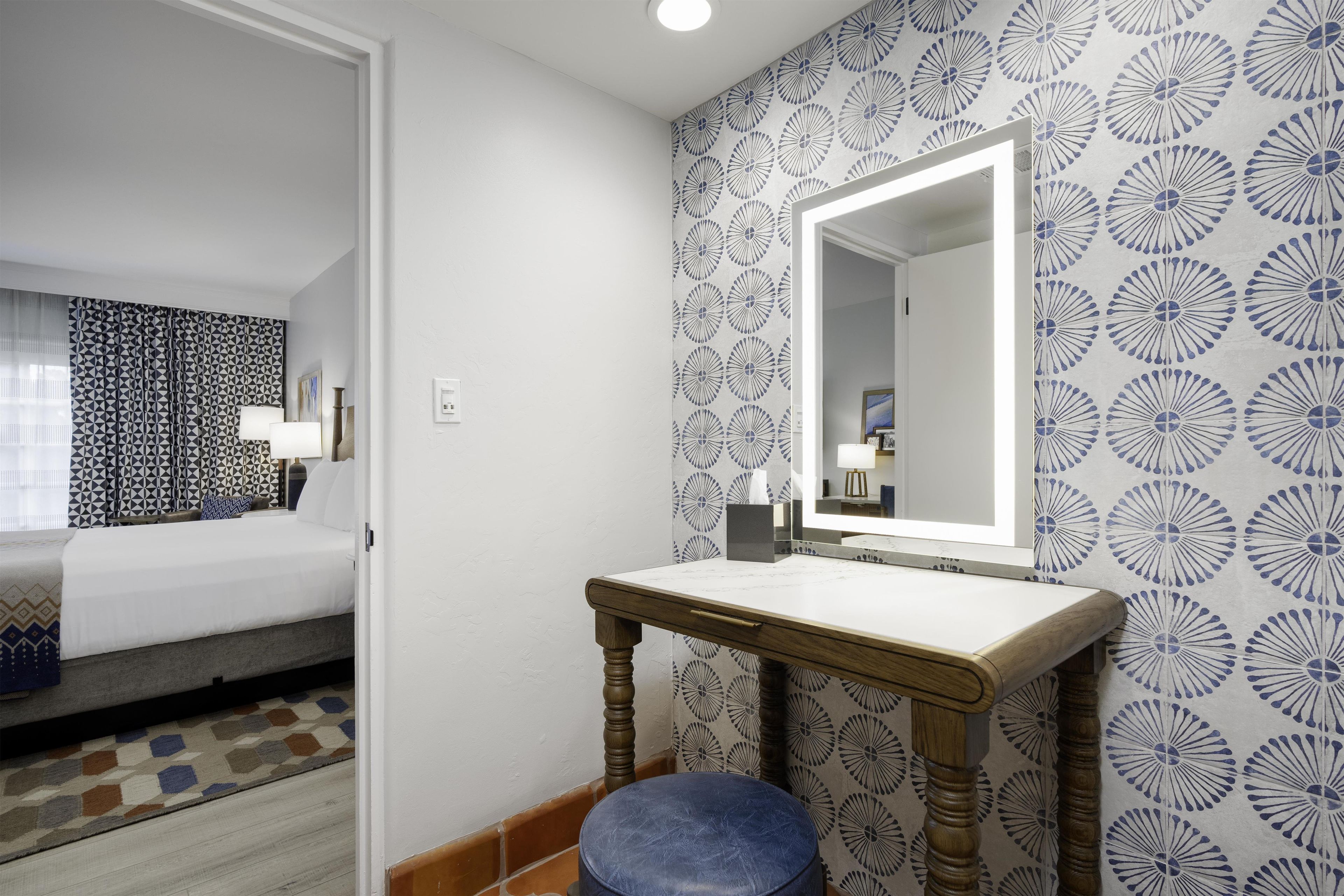 Une chambre d’hôtel avec un lit, une table de chevet, un miroir et un mur décoré d’un motif.