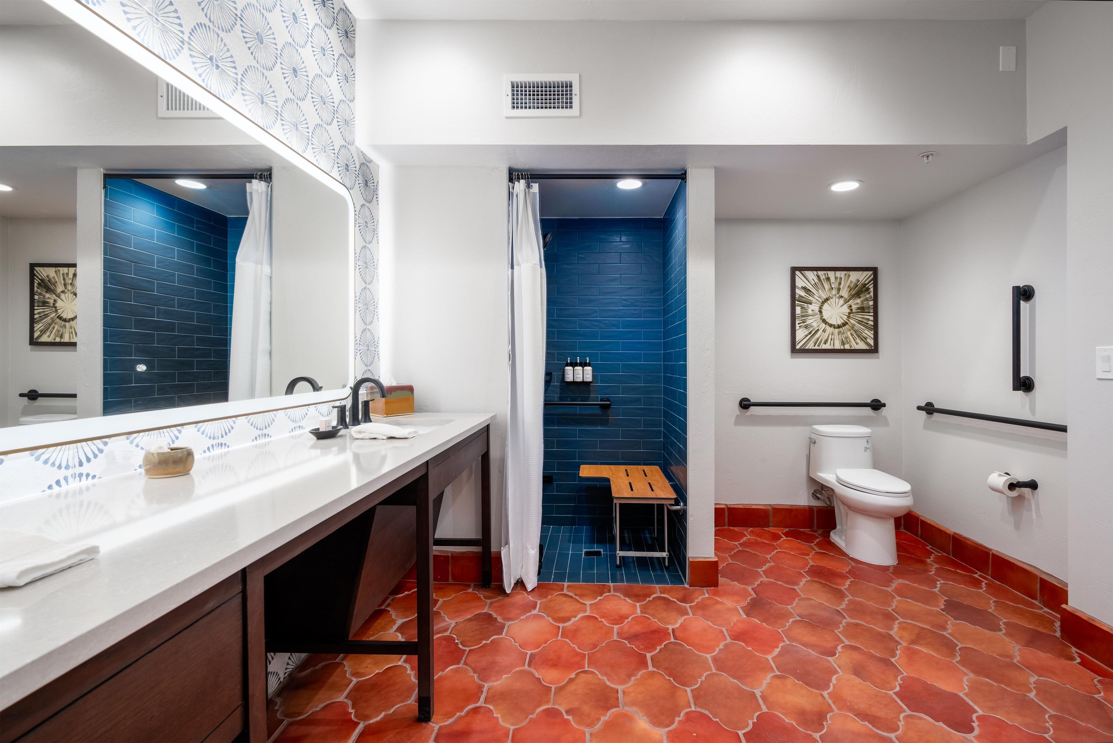 A modern bathroom with a white vanity, a blue shower enclosure, and a white toilet.