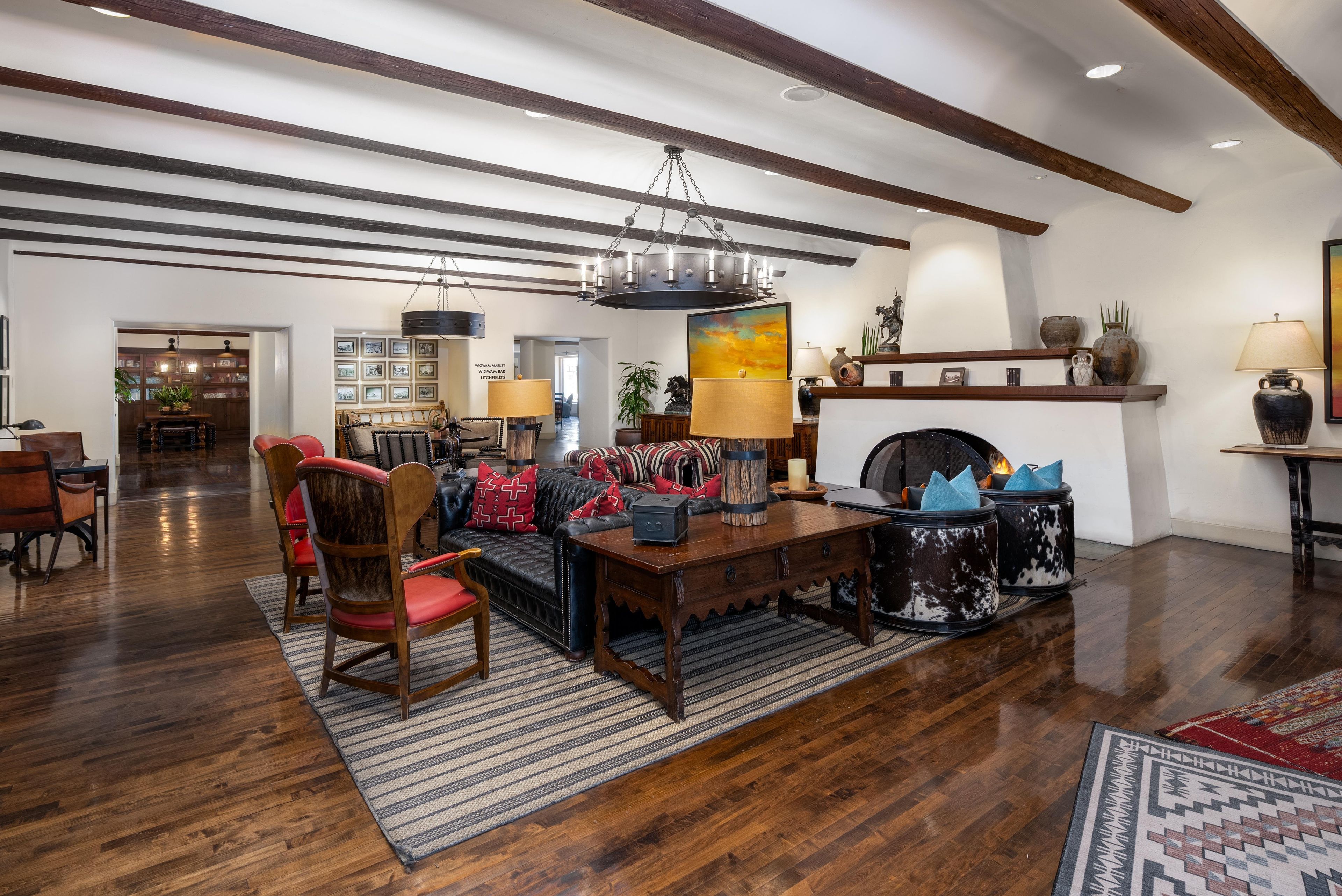 A spacious living room with a fireplace, wooden flooring, and a high ceiling with exposed beams.