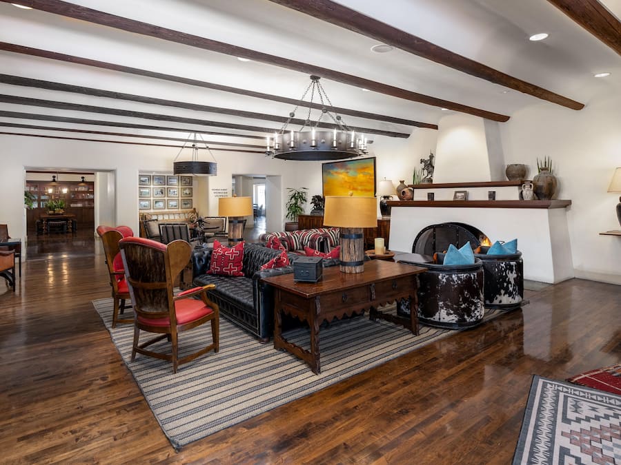 A spacious living room with a fireplace, wooden flooring, and a high ceiling with exposed beams.