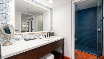 A bathroom with a white vanity, a large mirror, a round mirror, and a blue door.