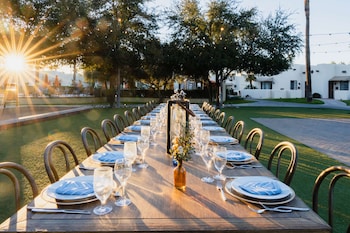 Formal outdoor dining area with a long table set for a special occasion, featuring a floral centerpiece and comfortable seating. at The Wigwam