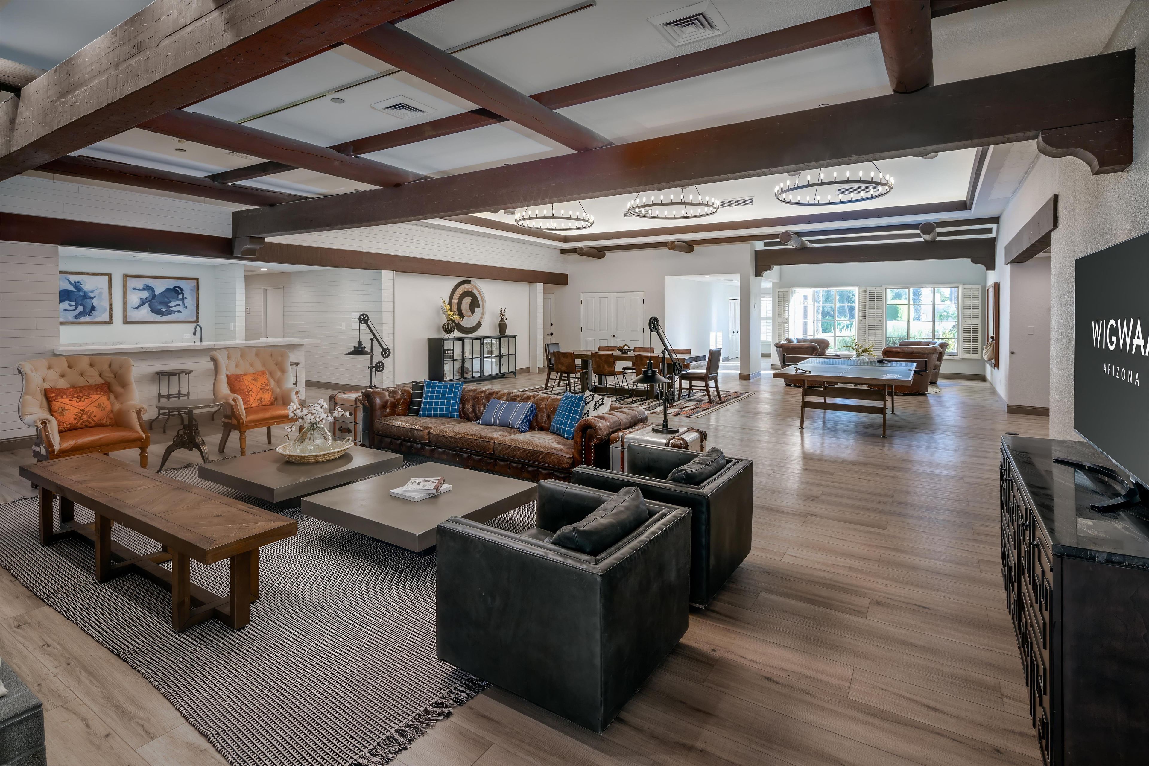 A spacious living area with a high ceiling, wooden beams, a fireplace, and a dining area with a pool table.