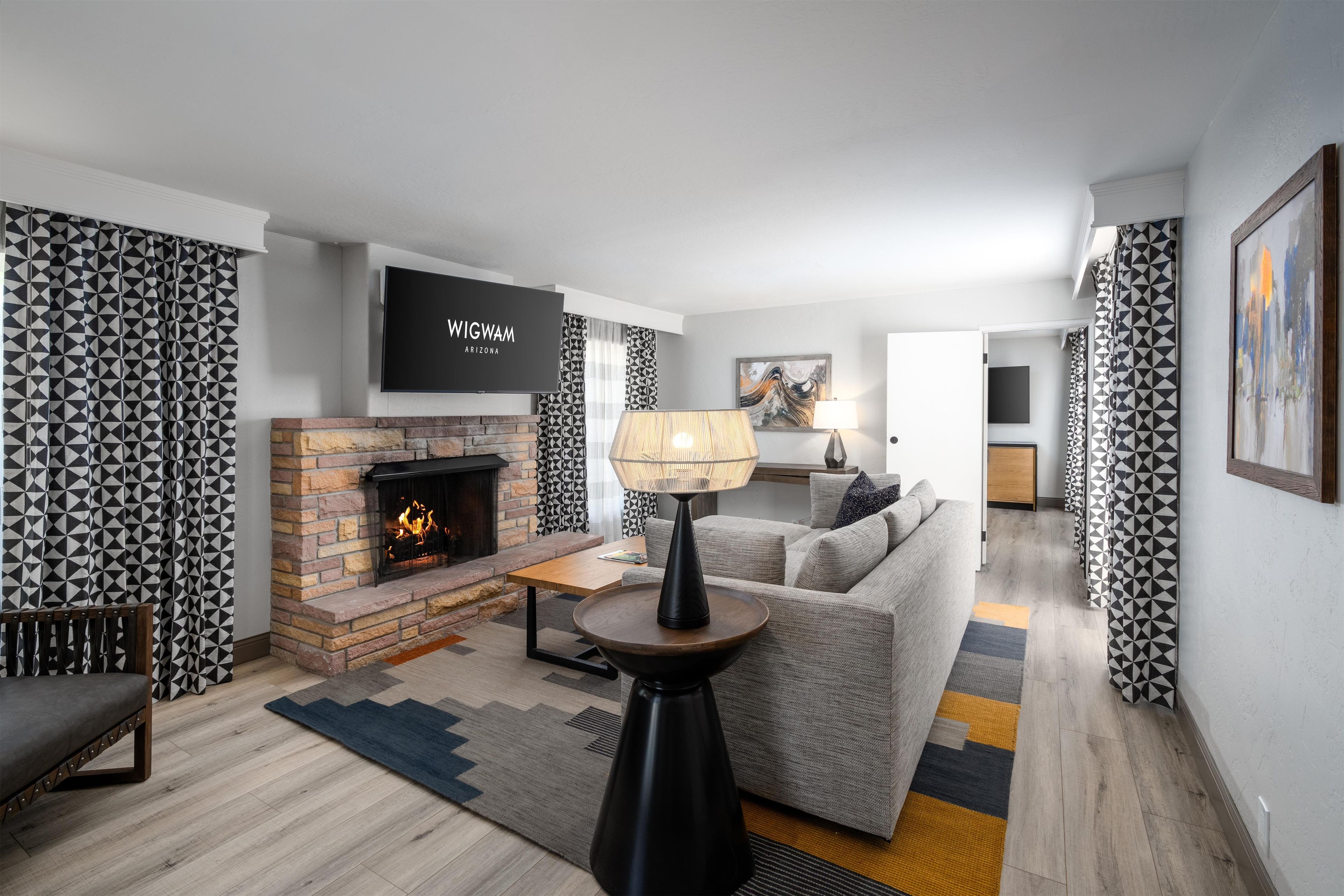 A modern living room with a fireplace, a sofa, a coffee table, and a TV mounted on the wall.