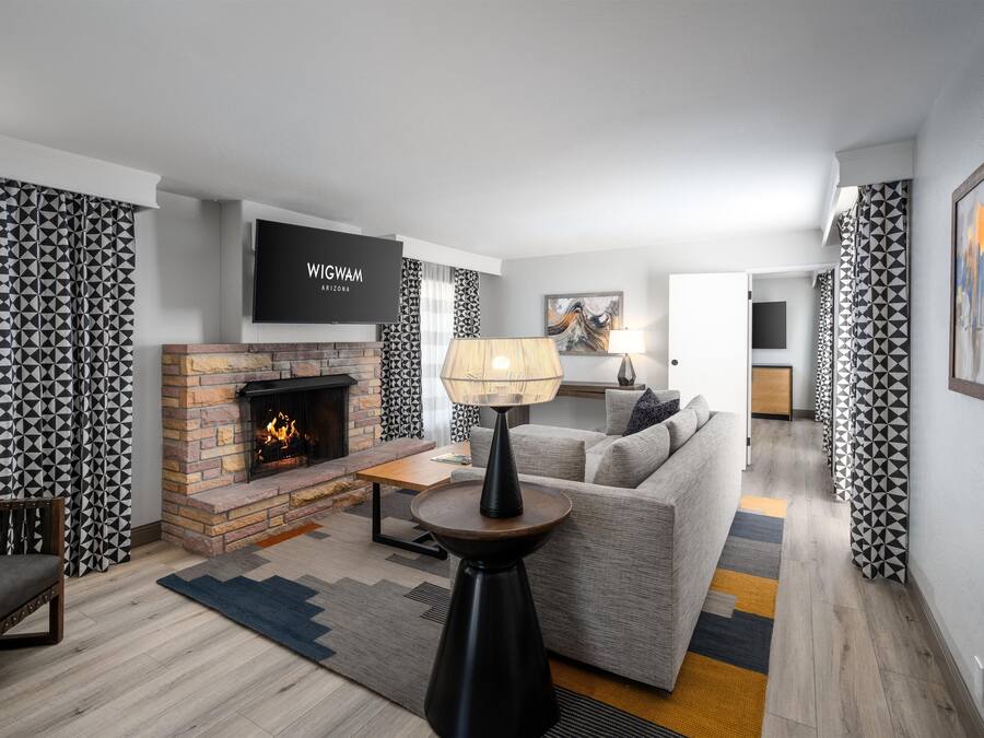 A modern living room with a fireplace, a sofa, a coffee table, and a TV mounted on the wall.