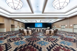 Ett konferensrum med en stor skärm som visar texten ”WIGWAM ARIZONA”, flera bord med stolar och en mönstrad matta.