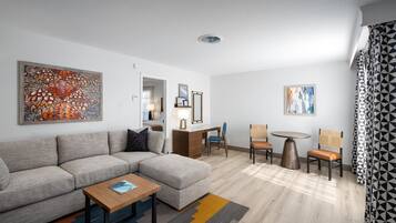 A modern living room with a sectional sofa, a small wooden table, and a dining area with chairs.