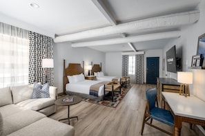 A hotel room with a bed, a sofa, a desk, and a TV. - The Wigwam (Litchfield Park)