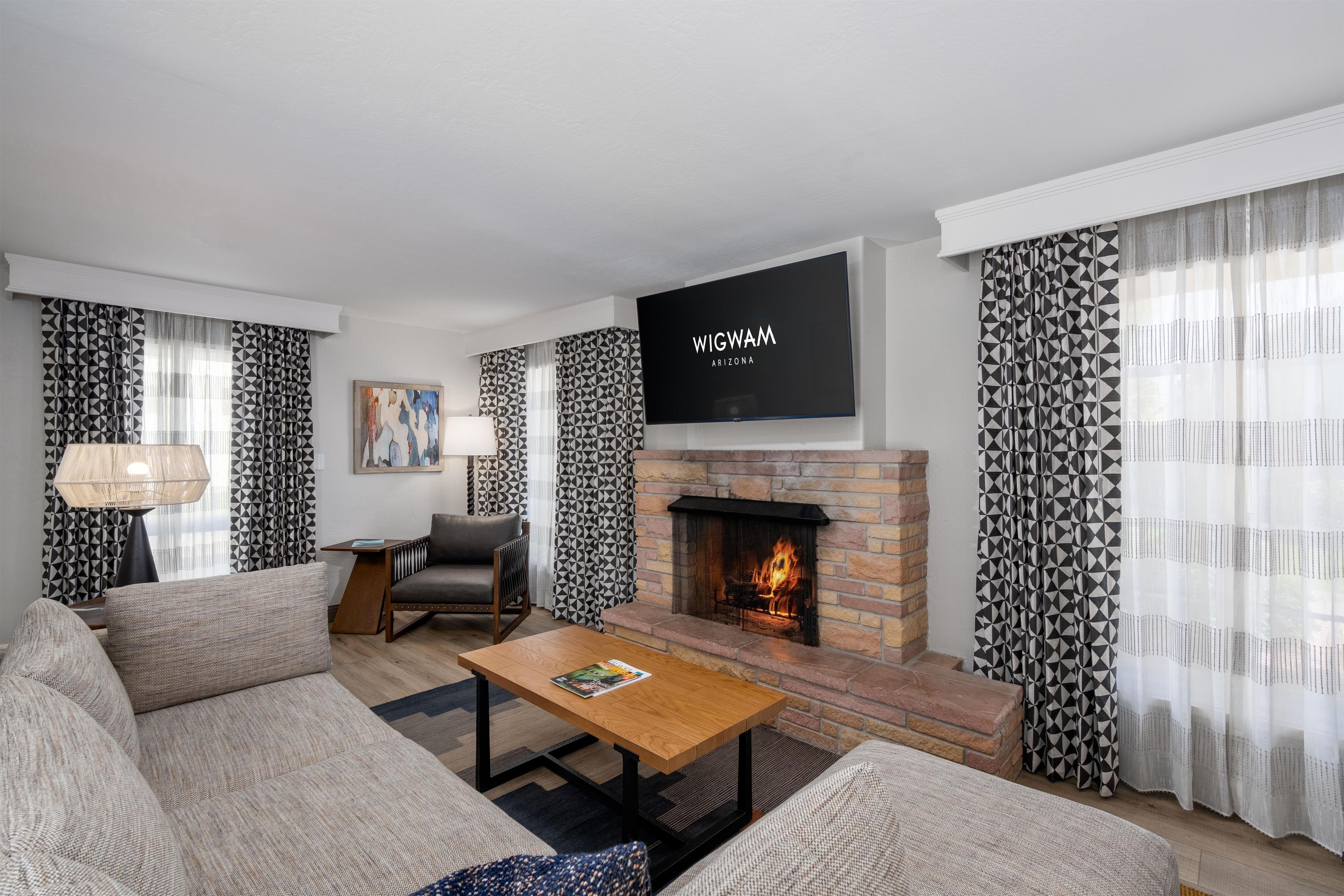 Una sala de estar moderna con chimenea, un televisor de pantalla plana y cortinas con estampado.