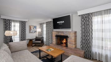 Una sala de estar moderna con chimenea, un televisor de pantalla plana y cortinas con estampado.