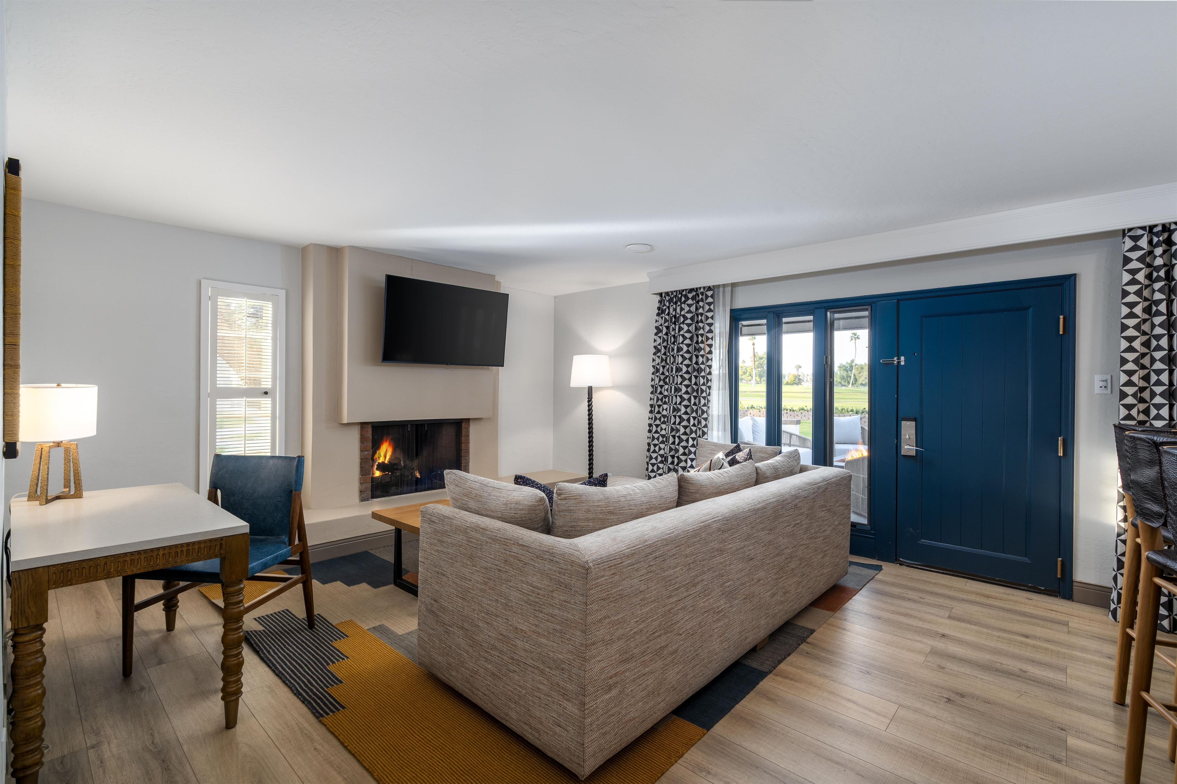 A modern living room with a sofa, a flat-screen TV, a fireplace, and a blue door.