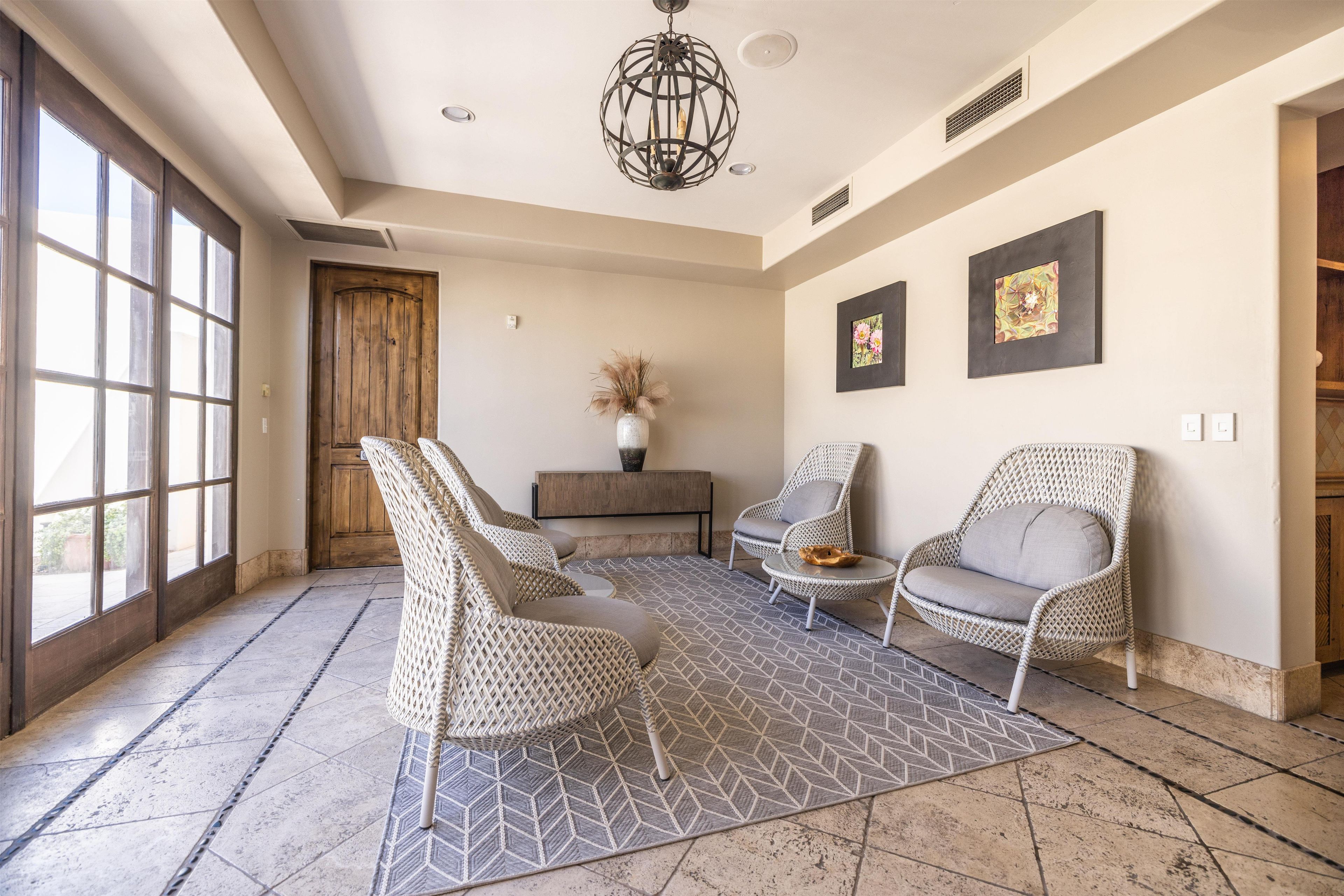 A spacious room with large windows, wicker furniture, and a patterned floor.