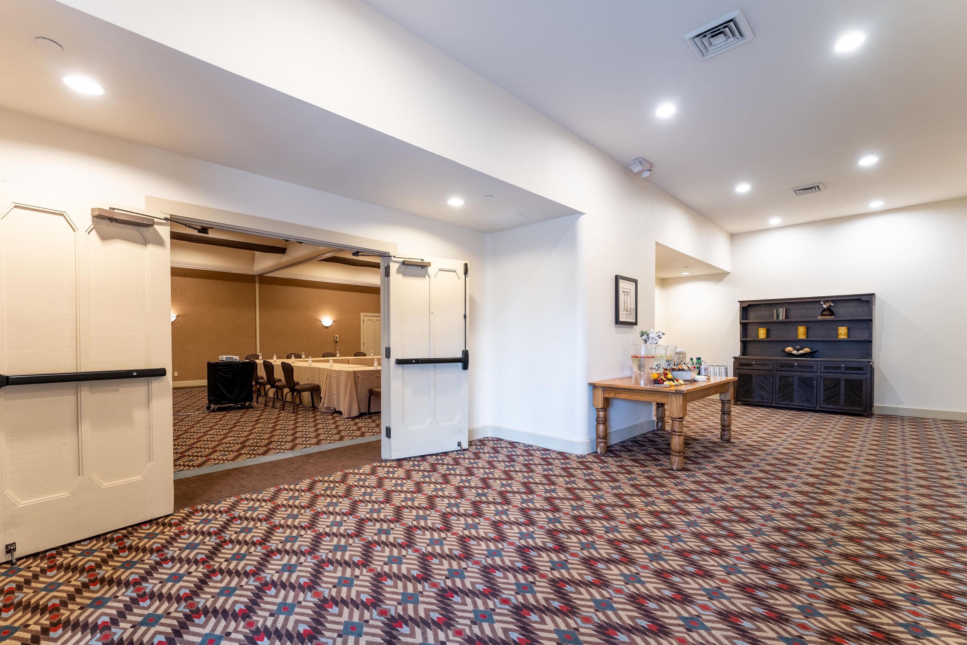 A conference room with a patterned carpet, a table with chairs, and a closed door.
