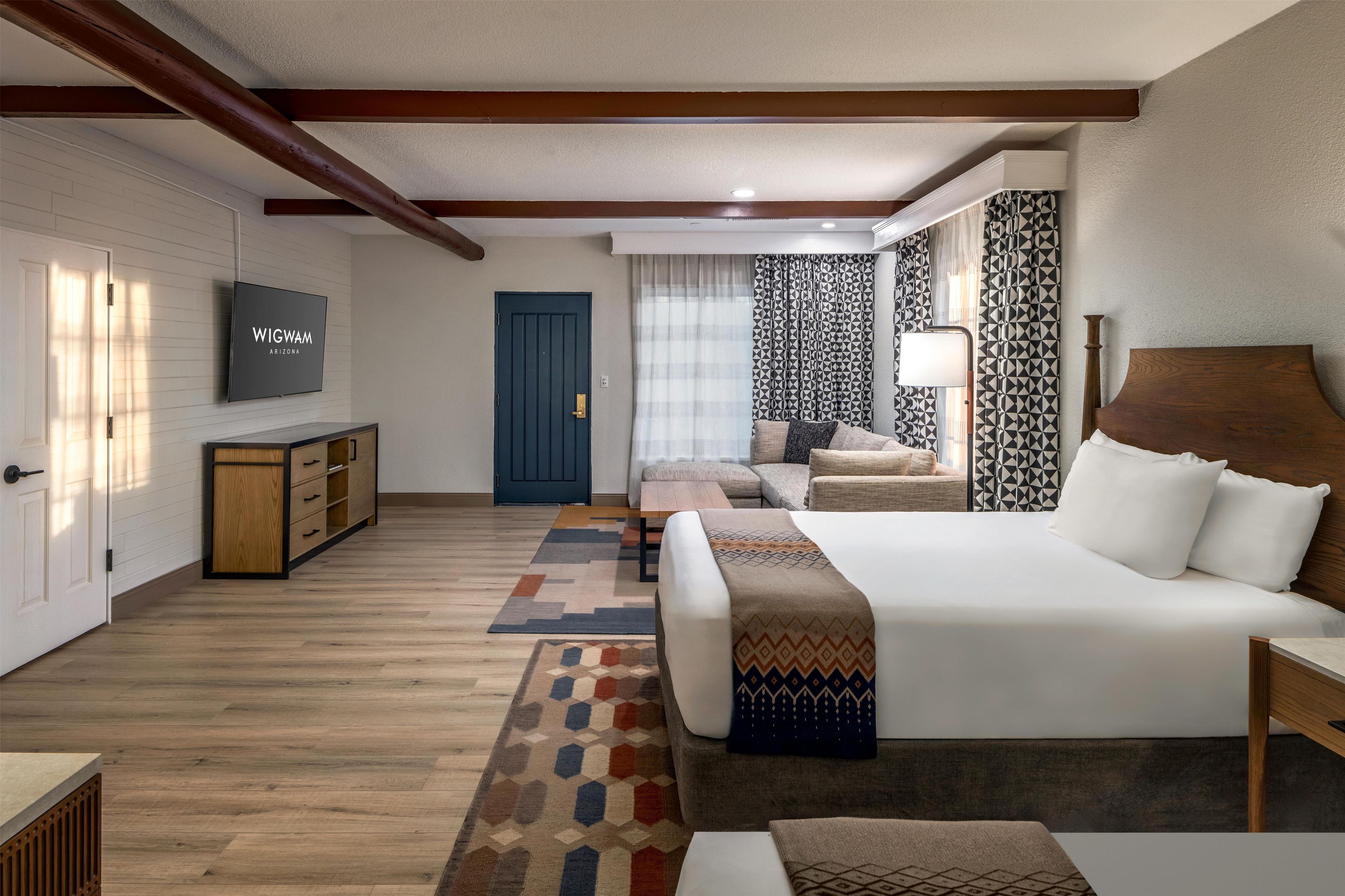 Una habitación de hotel con cama, televisión, sofá, escritorio y armario.