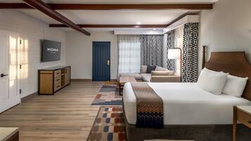 Una habitación de hotel con cama, televisión, sofá, escritorio y armario.