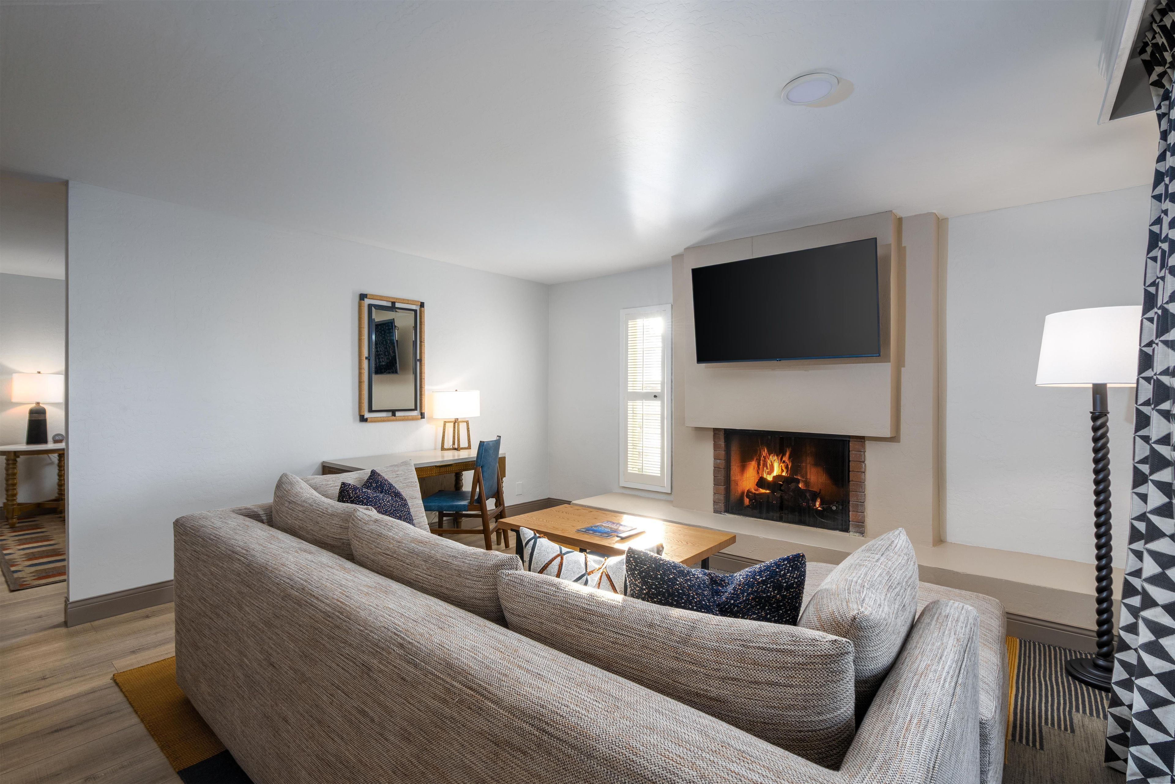 A living room with a sofa set, a flat-screen TV, a fireplace, and a dining area.