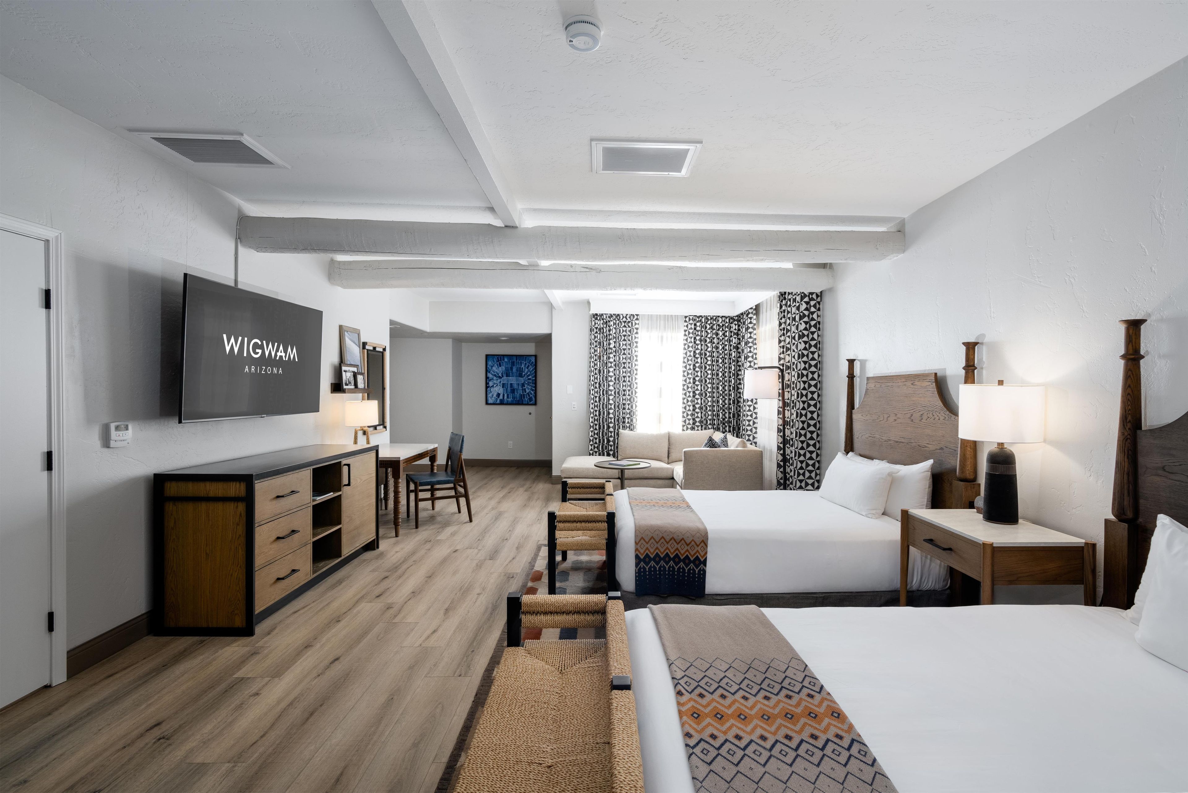 Una camera d'albergo moderna con TV a schermo piatto, un letto, una scrivania e un'area ristoro.