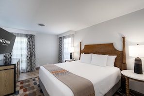 A hotel room with a bed, bedside tables, a desk, and a TV.