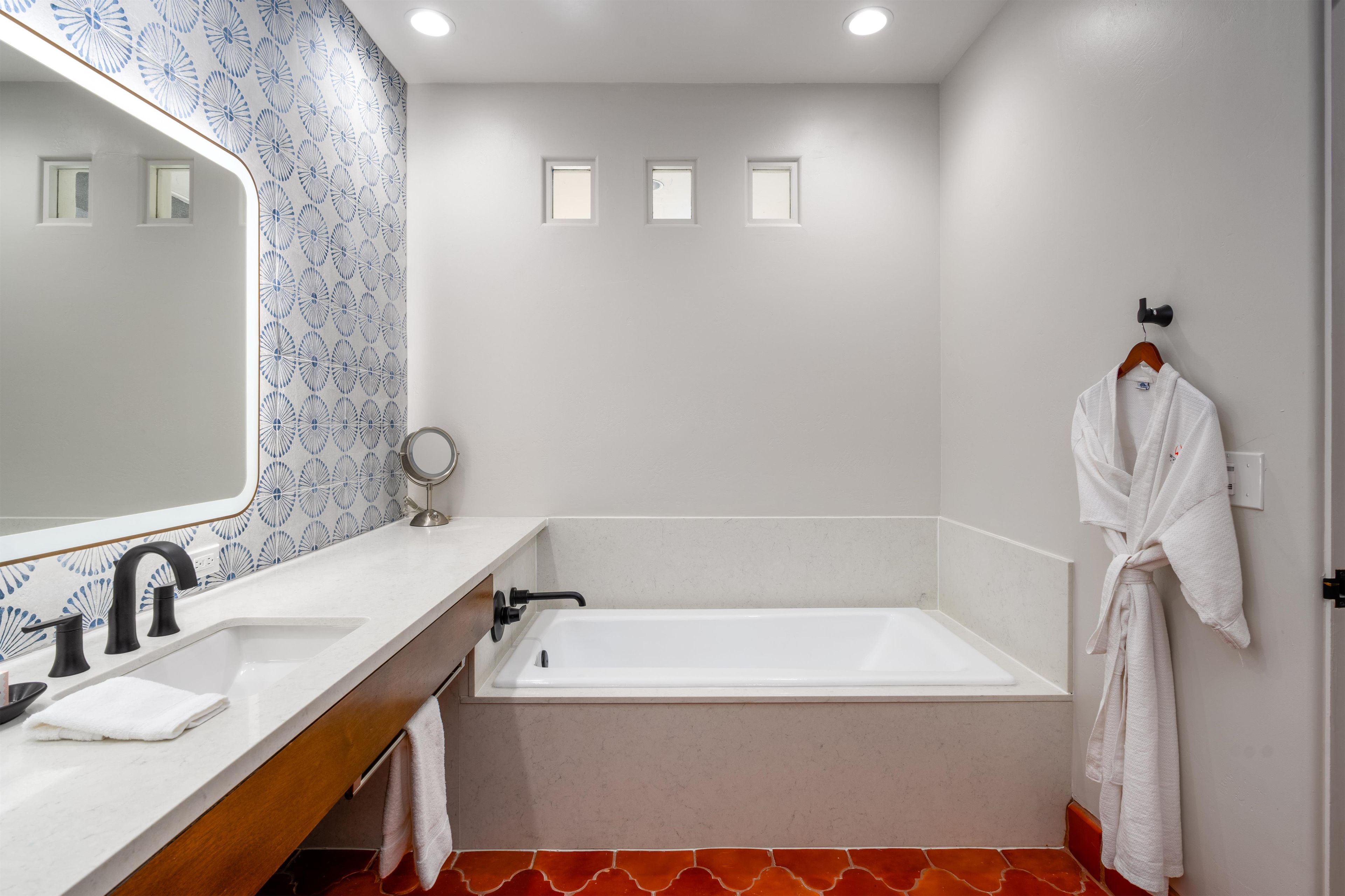 A modern bathroom with a bathtub, a vanity with a mirror, and a towel rack.