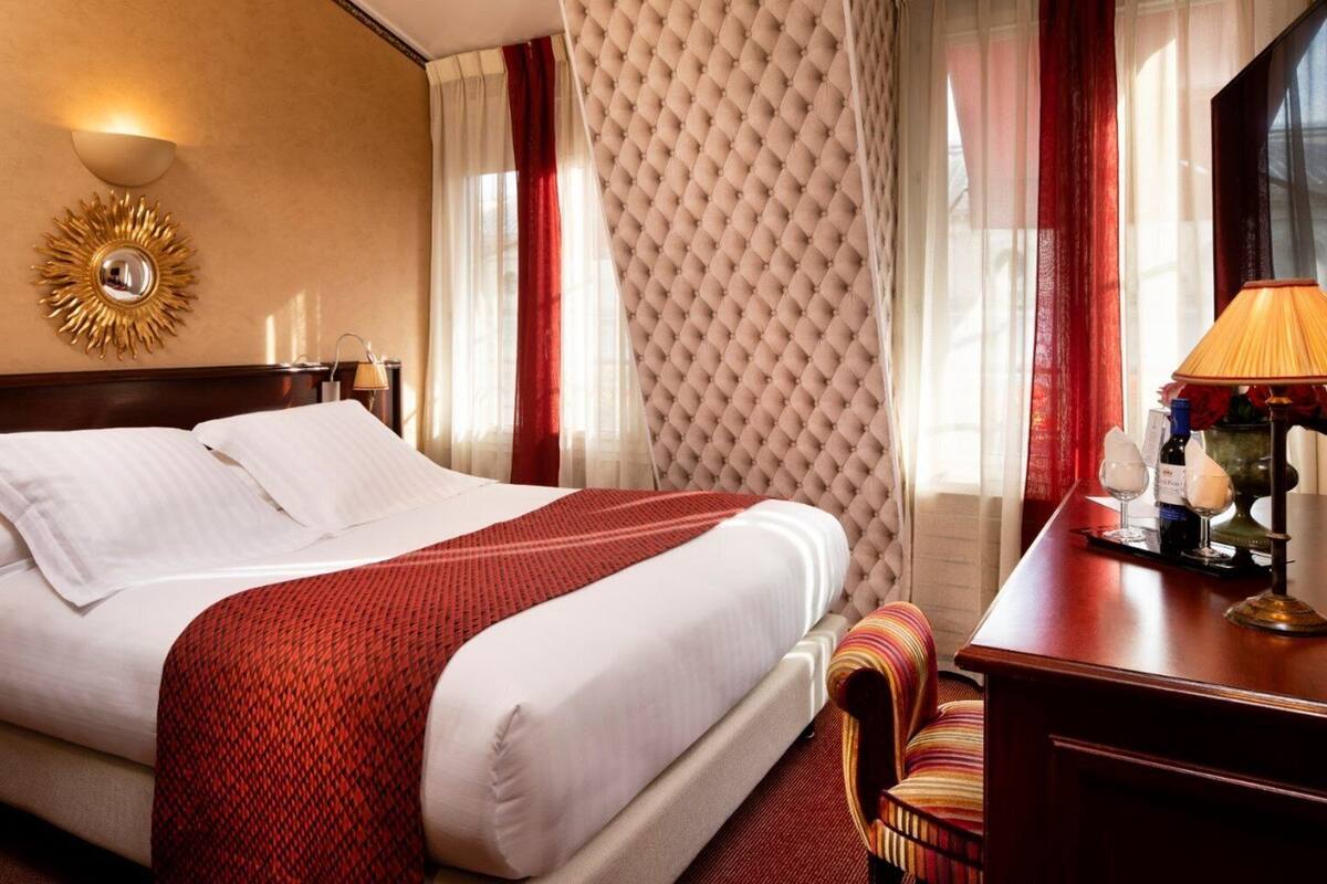 A hotel room with a large bed, a bedside table with a lamp, and a mirror on the wall.