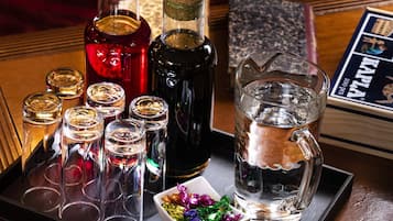 A tray with various bottles and glasses, a pitcher, and a small bowl of colorful items.