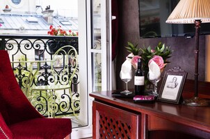 A wooden bar area with a red chair, a bottle of wine, a glass, and a framed picture.