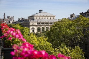 Un edificio histórico con una cúpula y ventanas arqueadas, rodeado de exuberante vegetación y plantas en flor.