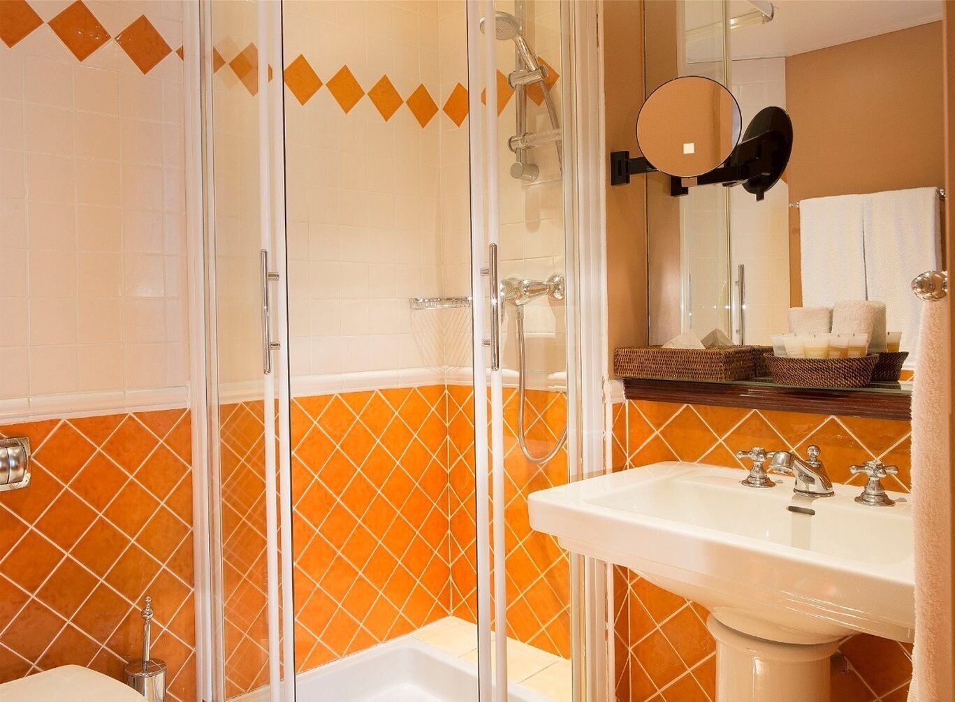 Een badkamer met een douche in een glazen cabine, een wastafel en een spiegel.