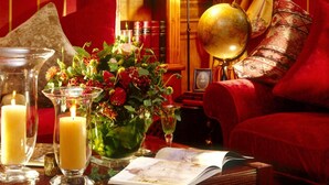 Um quarto aconchegante com um sofá vermelho, uma estante de madeira, um globo e velas.